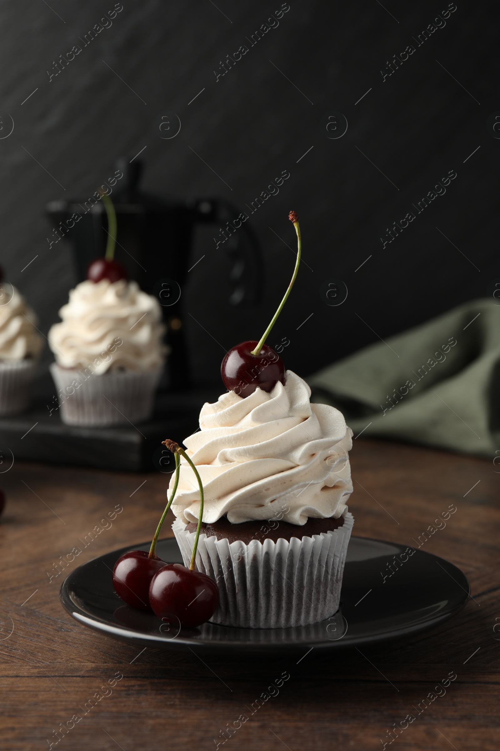 Photo of Delicious cupcake with cream and cherries on wooden table