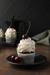 Delicious cupcake with cream and cherries on wooden table