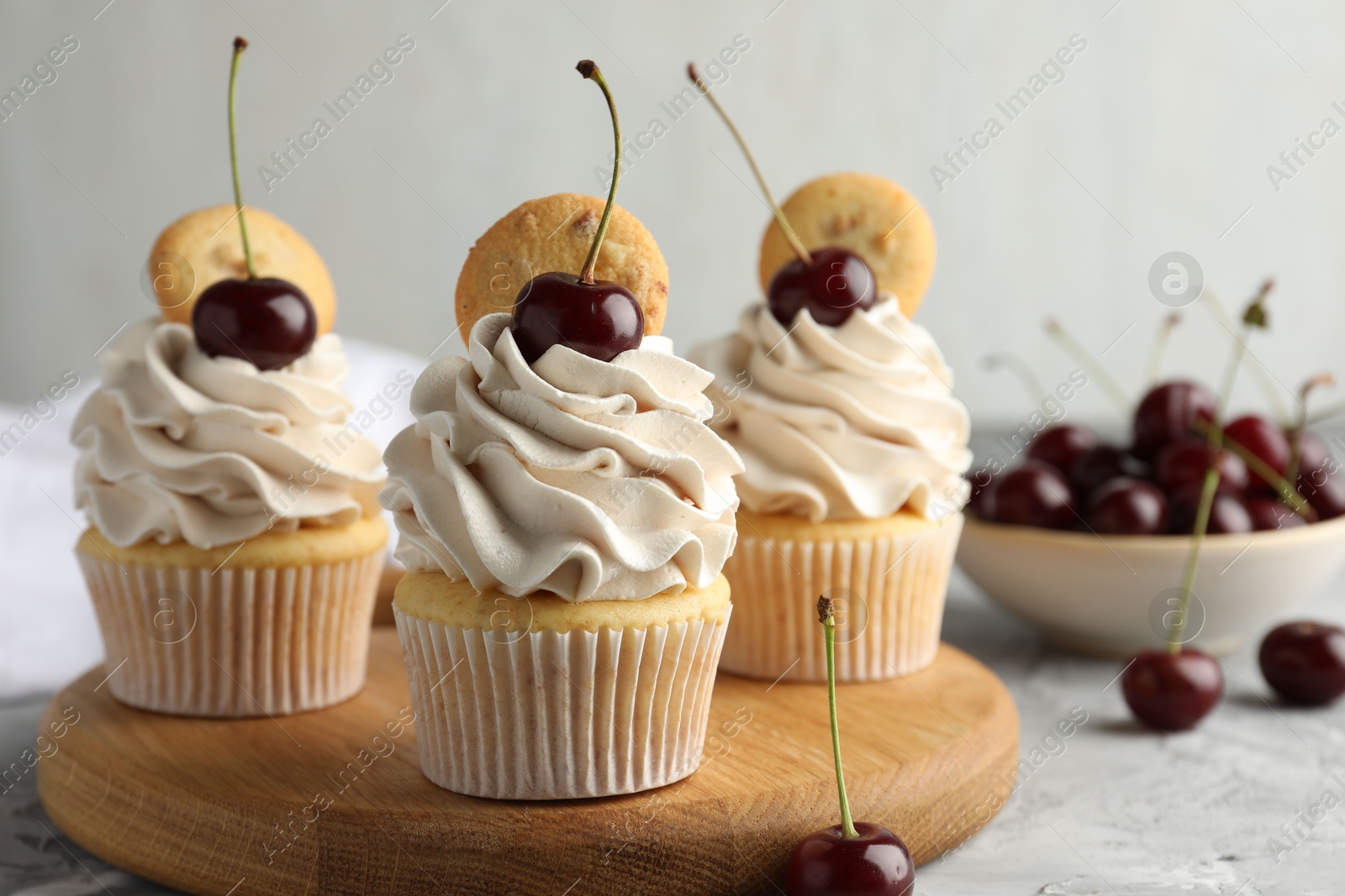 Photo of Delicious cupcakes with cherries and cookies on grey table, closeup