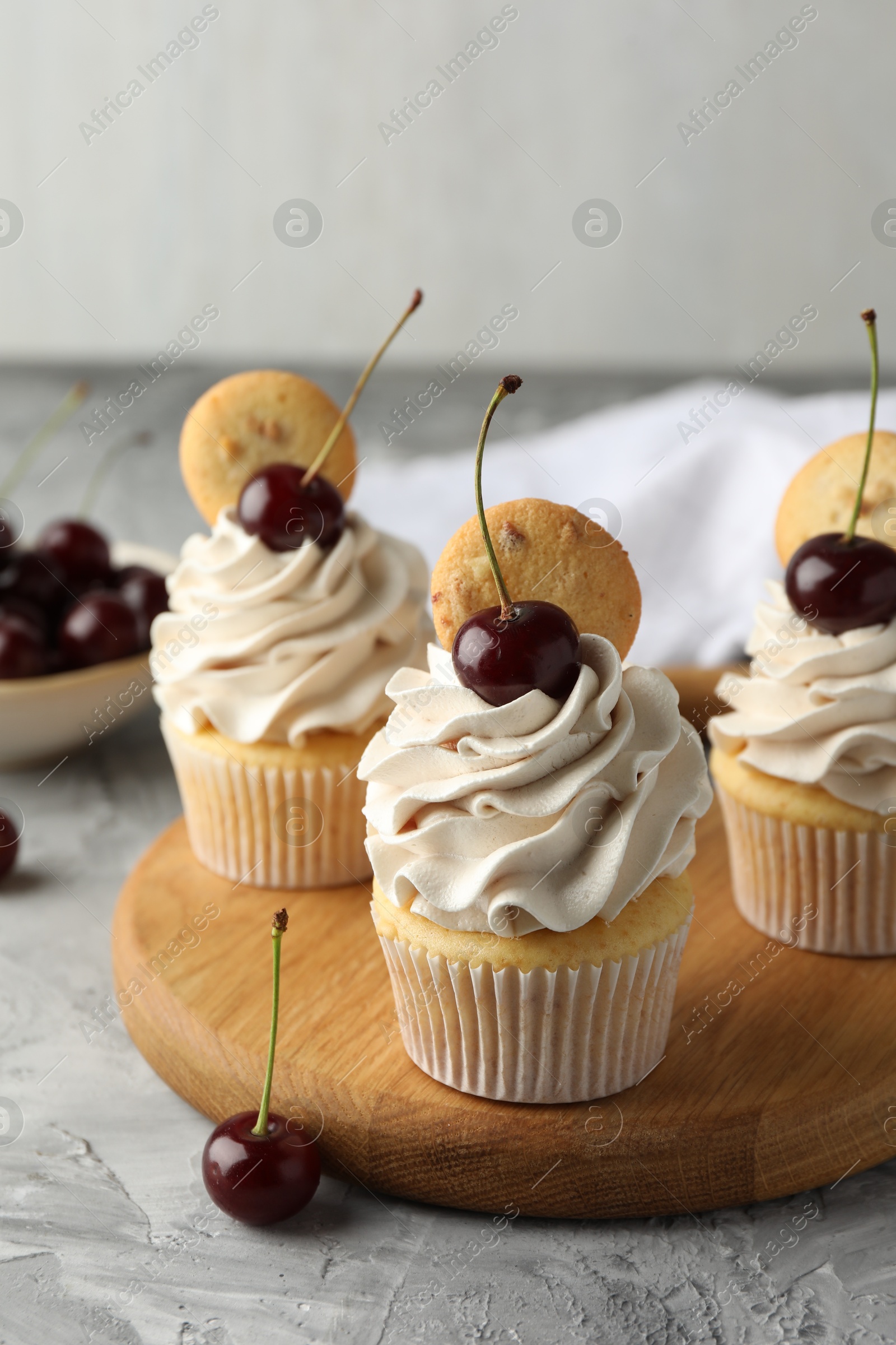 Photo of Delicious cupcakes with cherries and cookies on grey textured table