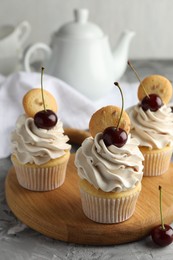 Photo of Delicious cupcakes with cherries and cookies on grey textured table