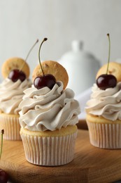 Delicious cupcakes with cherries and cookies on table, closeup