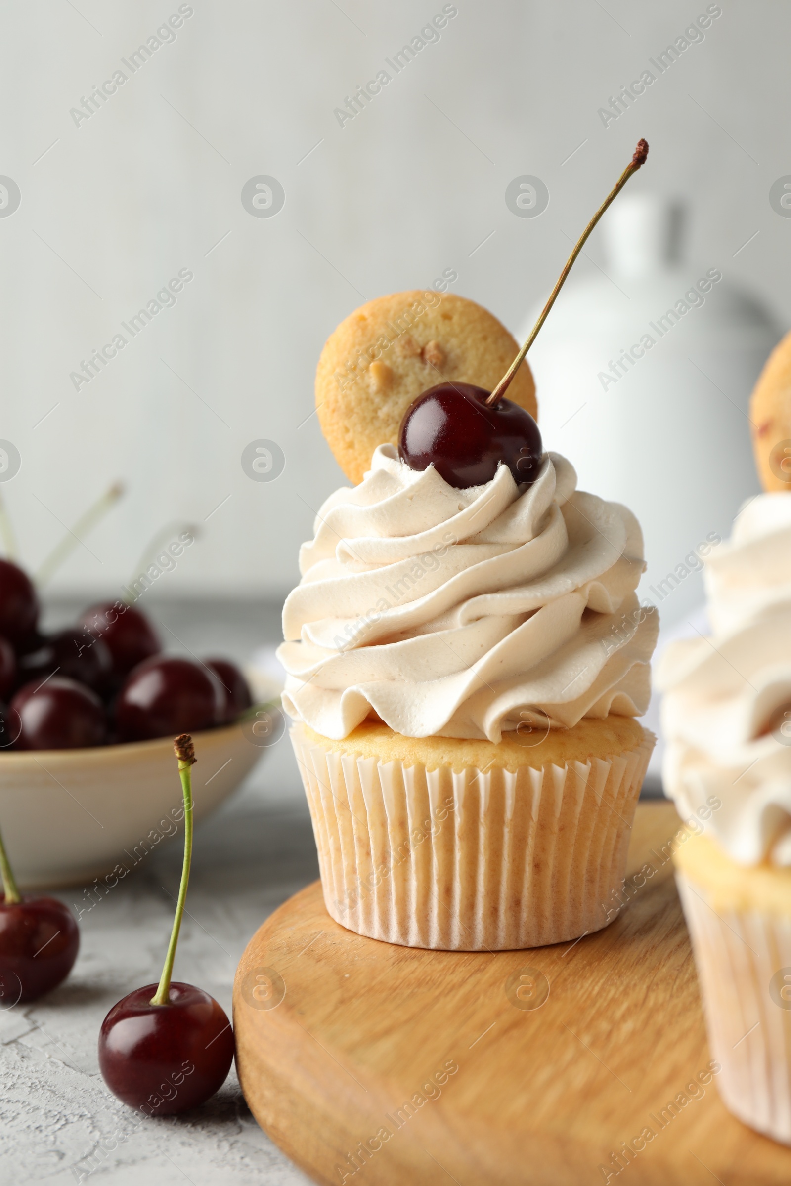 Photo of Delicious cupcakes with cherries and cookie on grey table, closeup