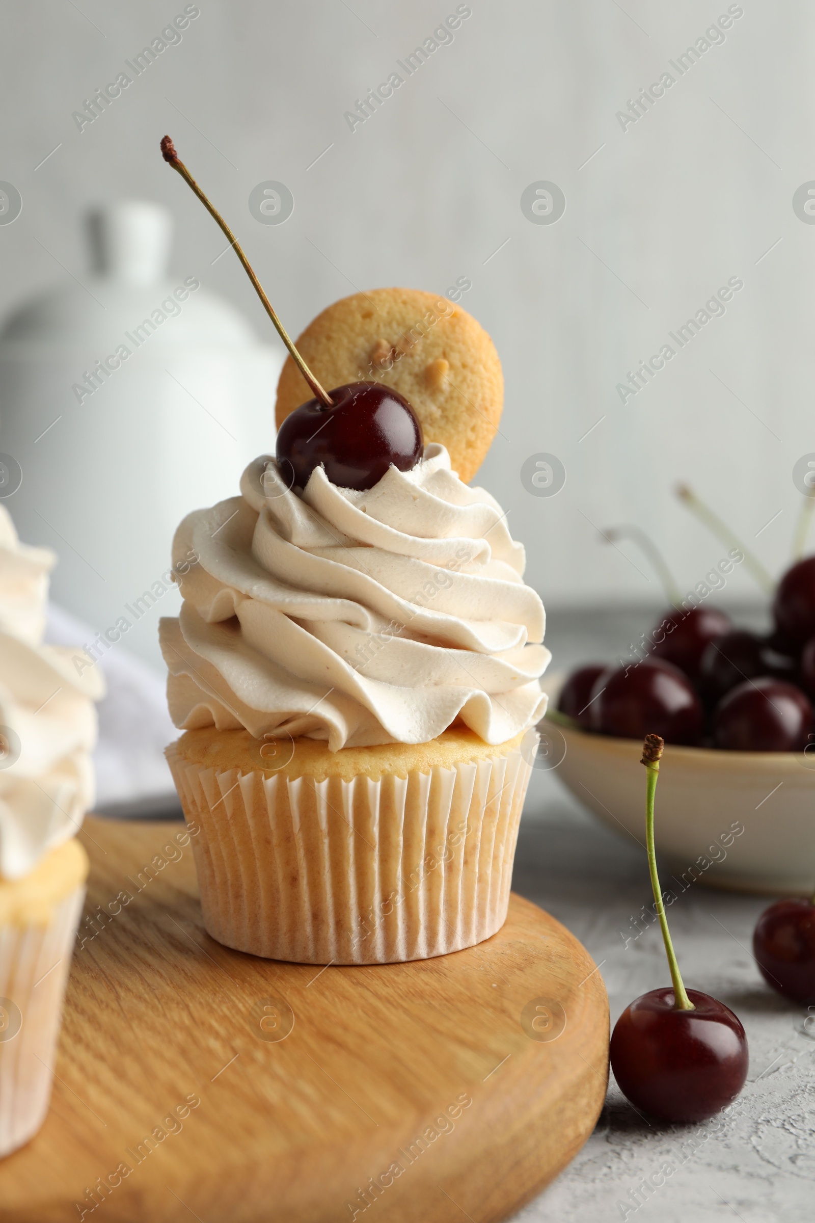 Photo of Delicious cupcakes with cherries and cookie on grey table, closeup