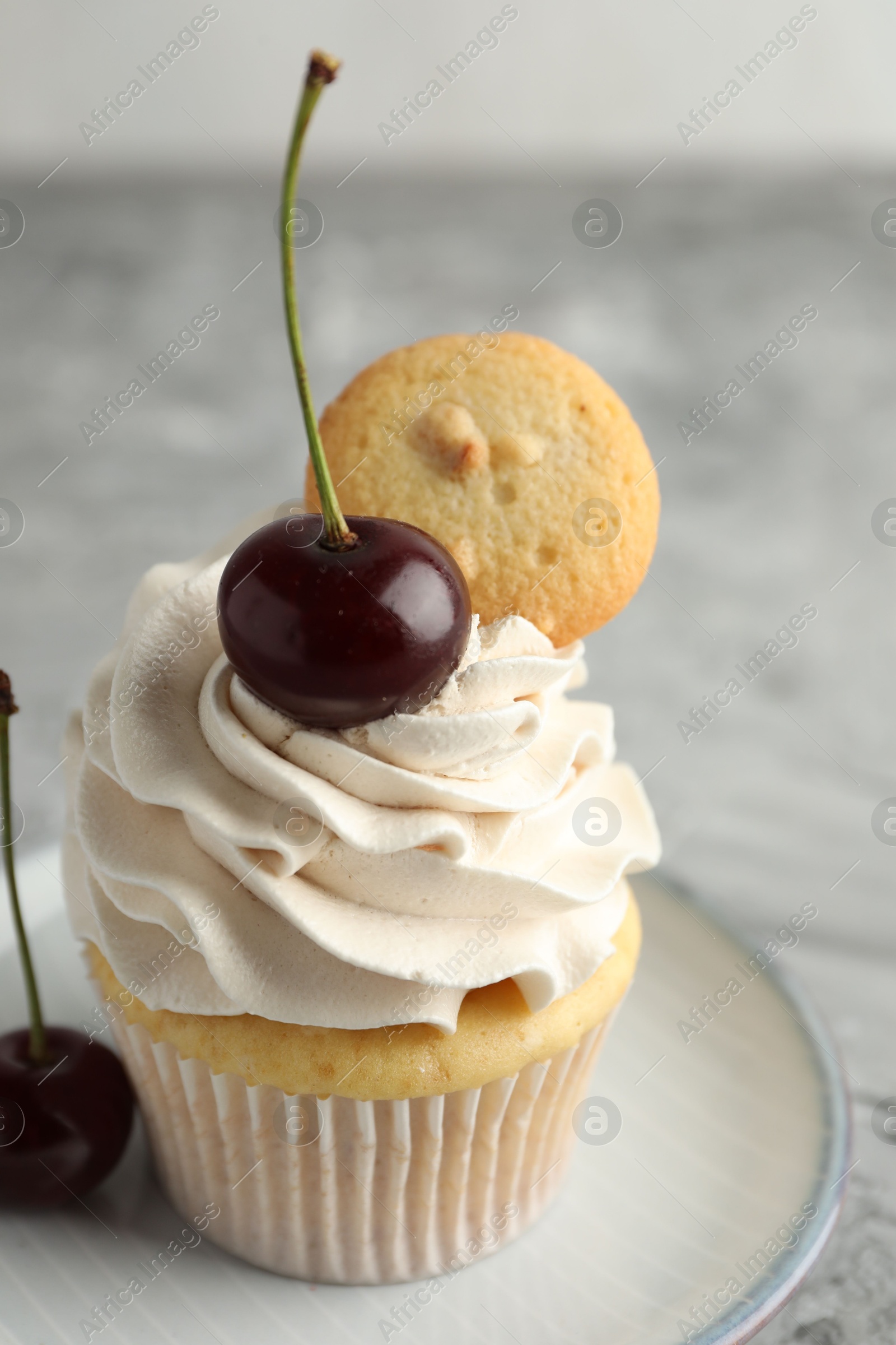 Photo of Delicious cupcake with cherries and cookie on grey table, closeup