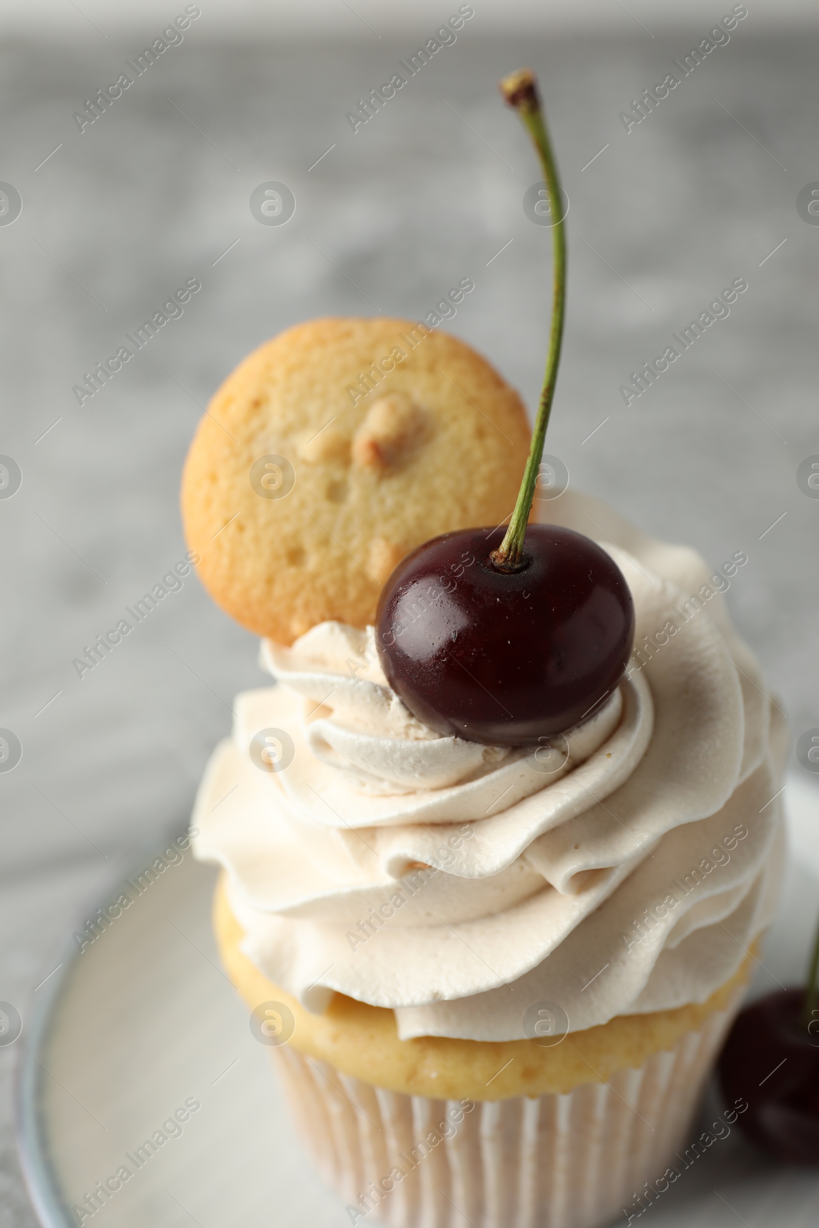 Photo of Delicious cupcake with cherries and cookie on grey table, closeup