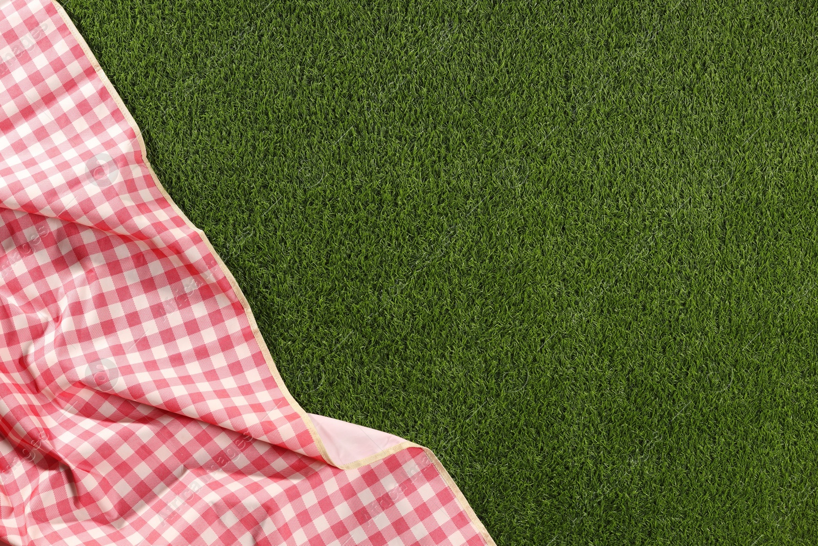Checkered picnic tablecloth on green grass, top view. Space for text Photo of Checkered picnic tablecloth on green grass, top view. Space for text