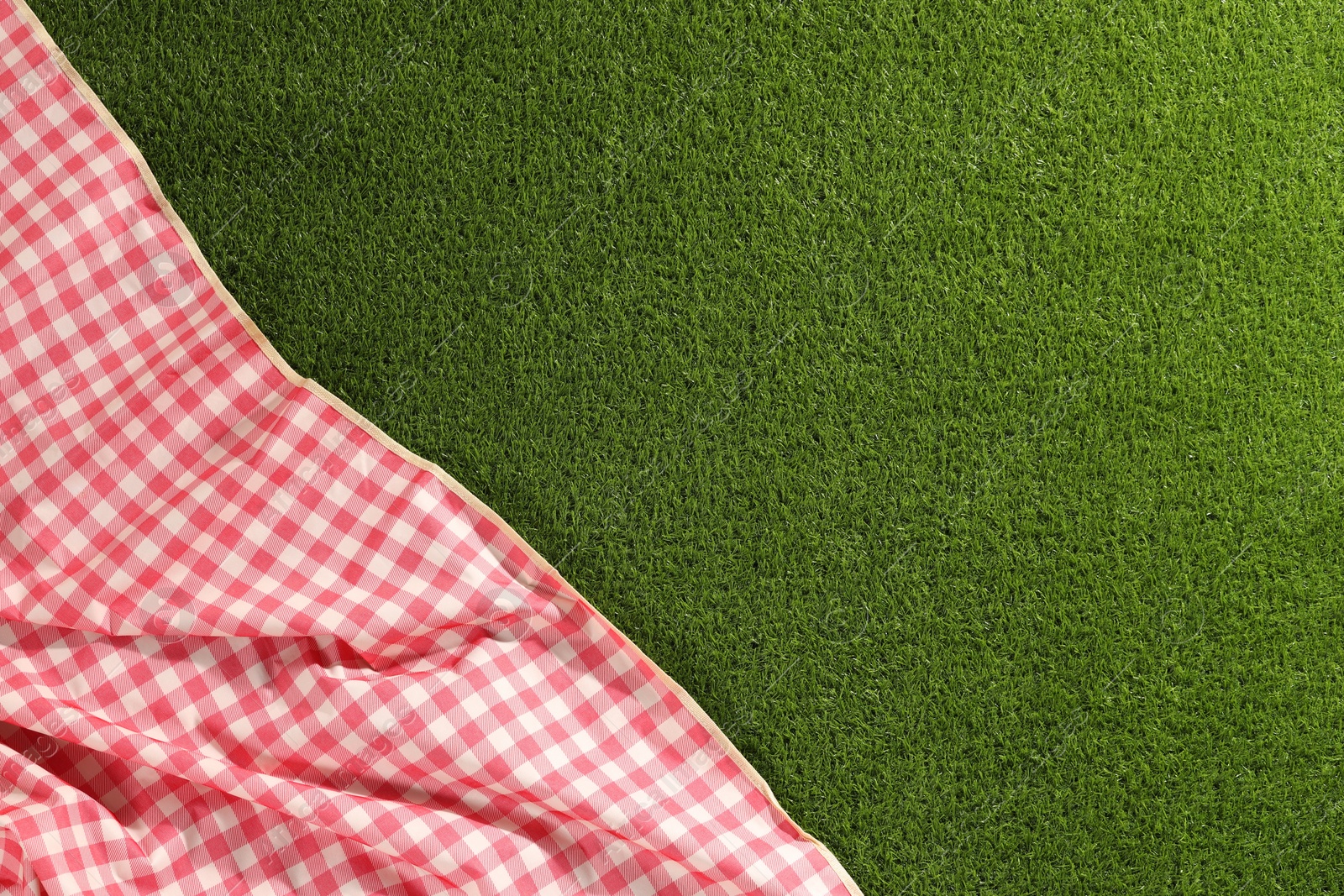 Checkered picnic tablecloth on green grass, top view. Space for text Photo of Checkered picnic tablecloth on green grass, top view. Space for text