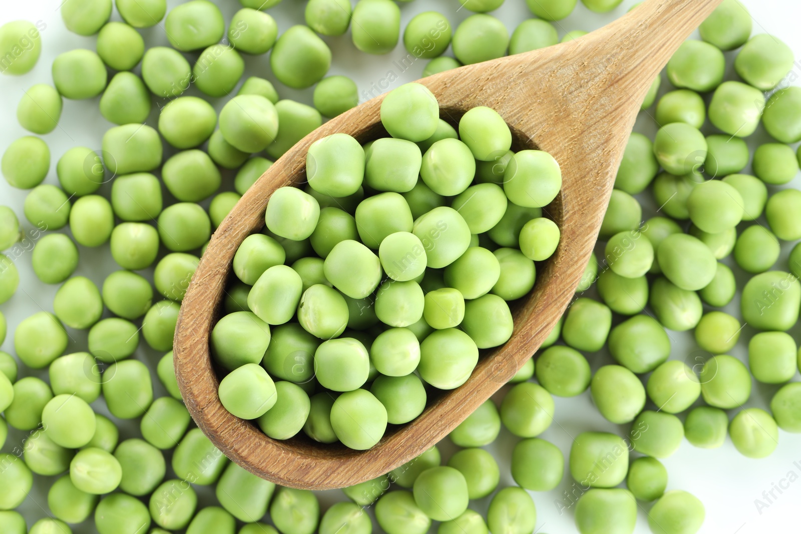 Photo of Fresh green peas and spoon on white background, top view