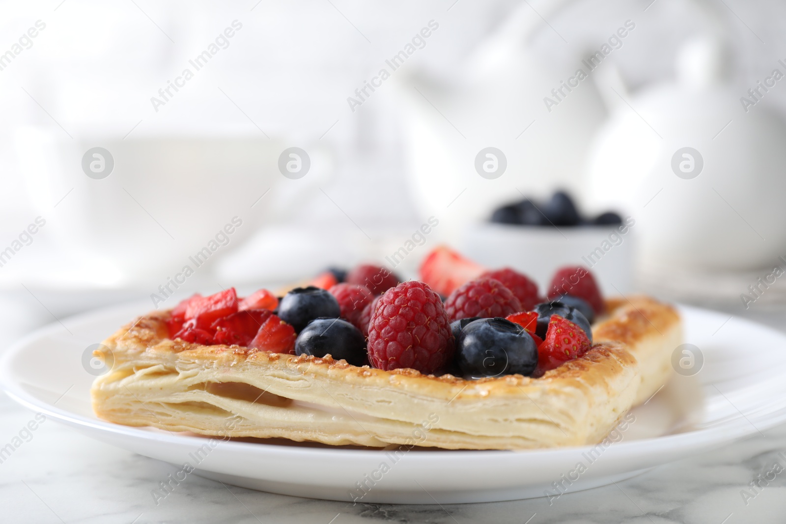 Photo of Tasty puff pastry with berries on white marble table, closeup