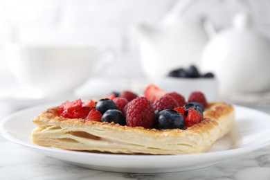 Photo of Tasty puff pastry with berries on white marble table, closeup