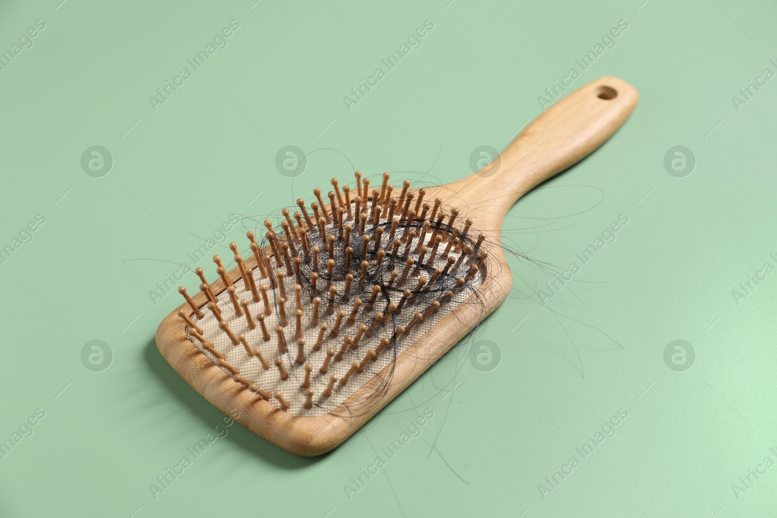 Photo of Wooden brush with lost hair on green background