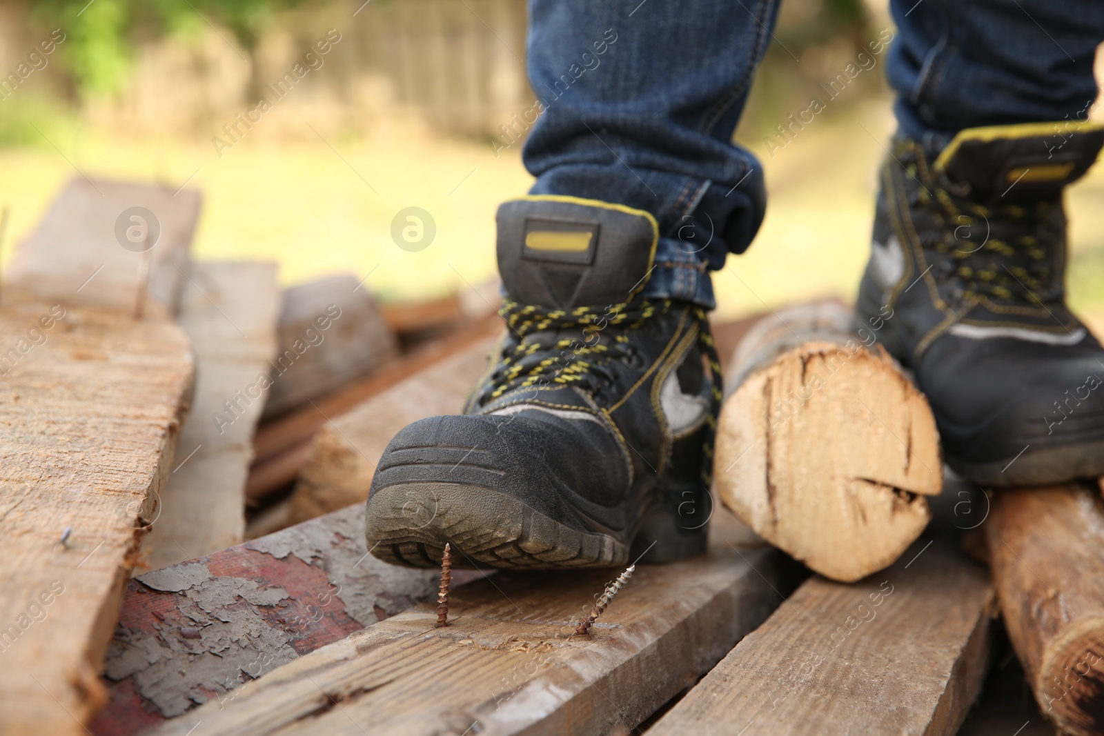 Photo of Careless worker stepping on nail in wooden plank outdoors, closeup