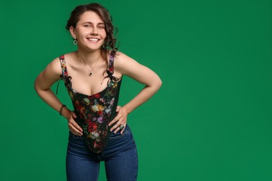 Photo of Smiling woman in stylish corset on green background. Space for text