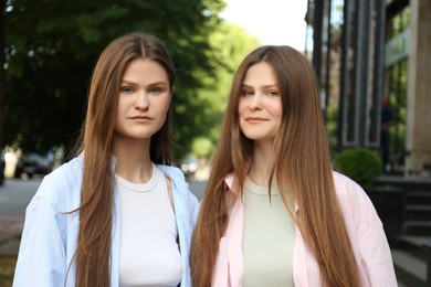 Photo of Portrait of two beautiful twin sisters outdoors