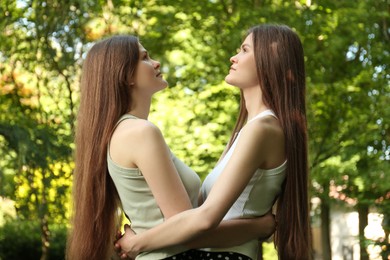 Photo of Two beautiful twin sisters spending time together in park