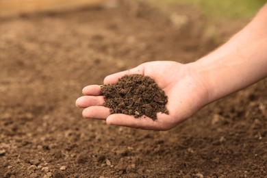 Woman holding pile of soil outdoors, closeup. Space for text