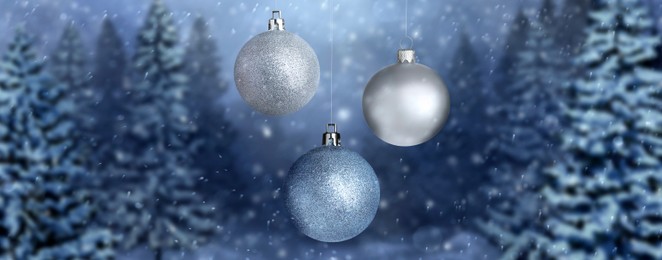 Image of Beautiful Christmas balls against snowy forest, banner design