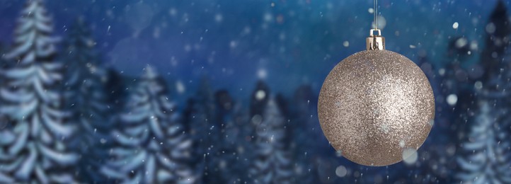 Image of Shiny Christmas ball against snowy forest, banner design. Space for text