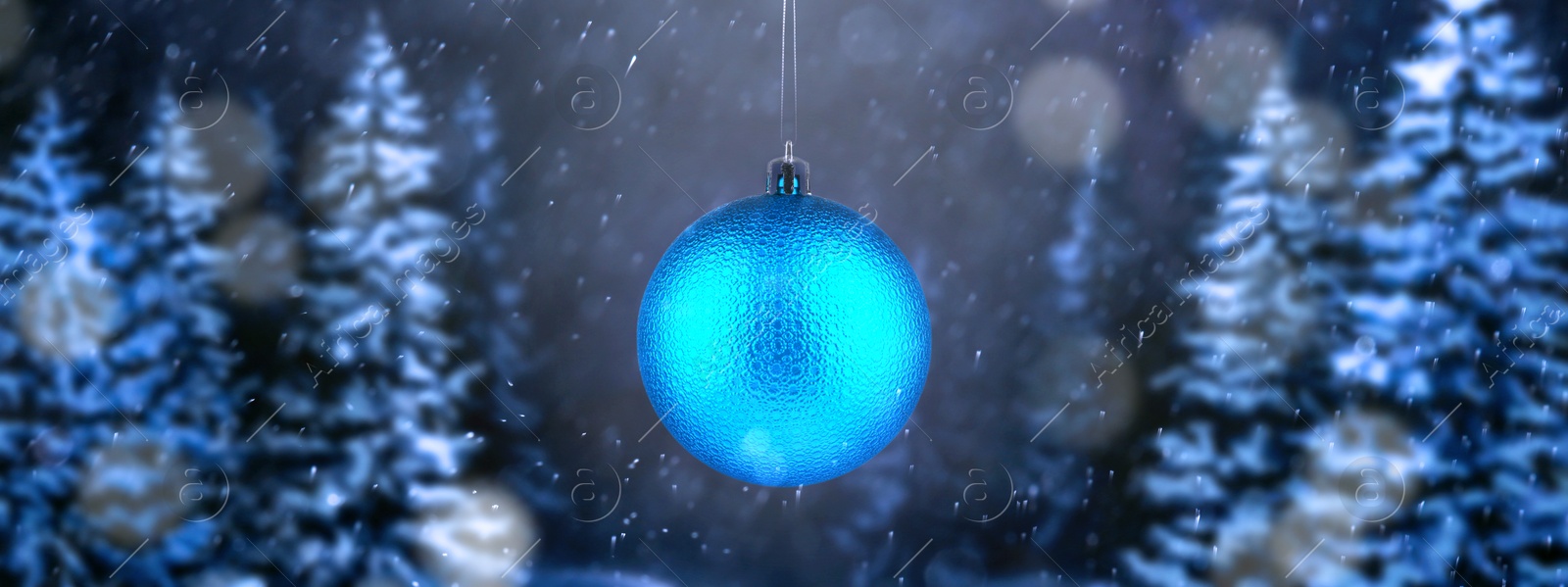 Image of Light blue Christmas ball against snowy forest, banner design