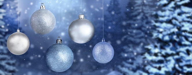 Image of Beautiful Christmas balls against snowy forest, banner design. Space for text