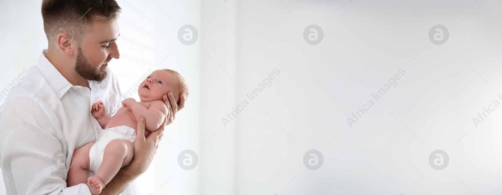 Image of Father holding his small baby indoors. Banner design with space for text