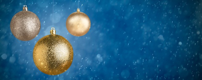 Image of Christmas balls against blurred snowy background, space for text. Banner design