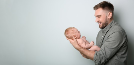 Image of Father holding his small baby on light background. Banner design with space for text