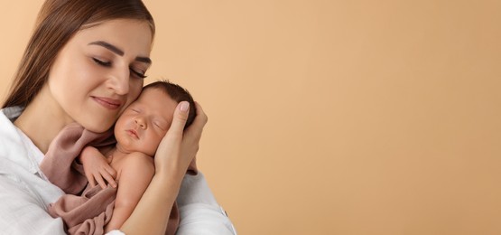 Mother holding her small baby on beige background. Banner design with space for text
