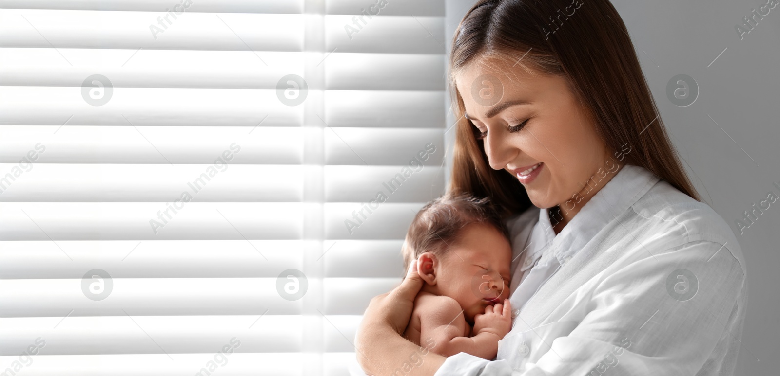 Image of Mother holding her small baby indoors. Banner design with space for text