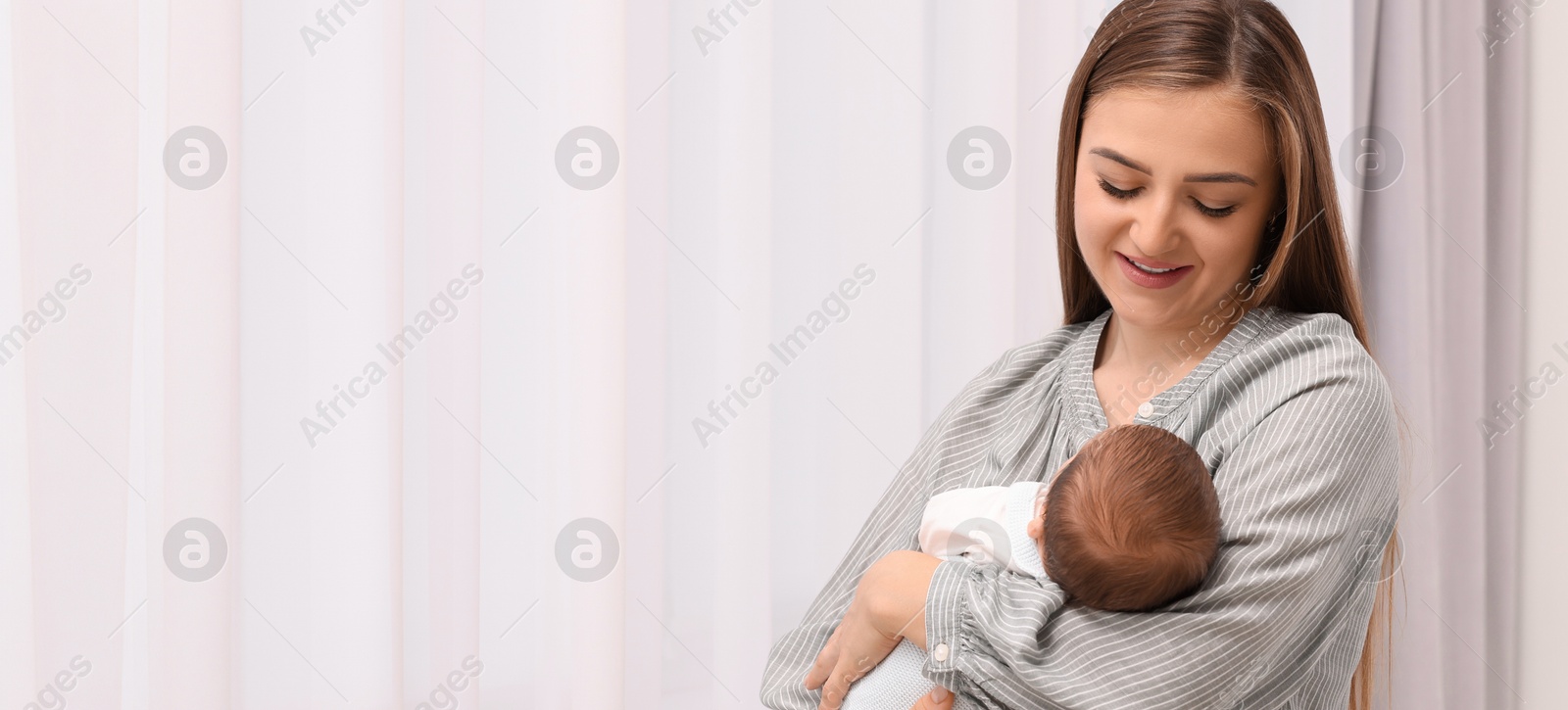 Image of Mother holding her small baby indoors. Banner design with space for text