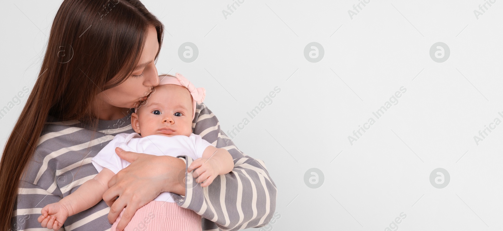 Image of Mother holding her small baby on light background. Banner design with space for text