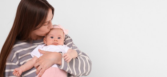 Mother holding her small baby on light background. Banner design with space for text