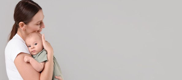 Image of Mother holding her small baby on light grey background. Banner design with space for text