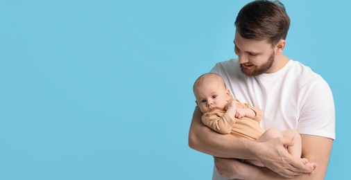 Image of Father holding his small baby on light blue background. Banner design with space for text