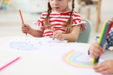 Little children drawing with colorful pencils at white table in kindergarten, closeup