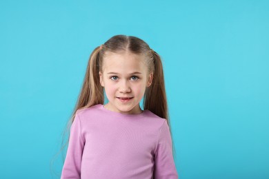 Photo of Portrait of cute little girl on light blue background