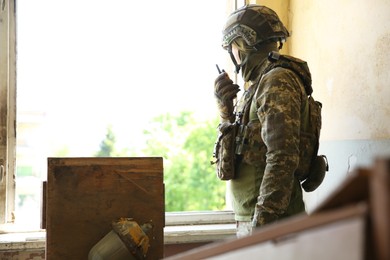 Military mission. Soldier in uniform with radio transmitter inside abandoned building