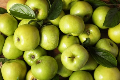 Photo of Fresh ripe green apples with leaves as background, top view