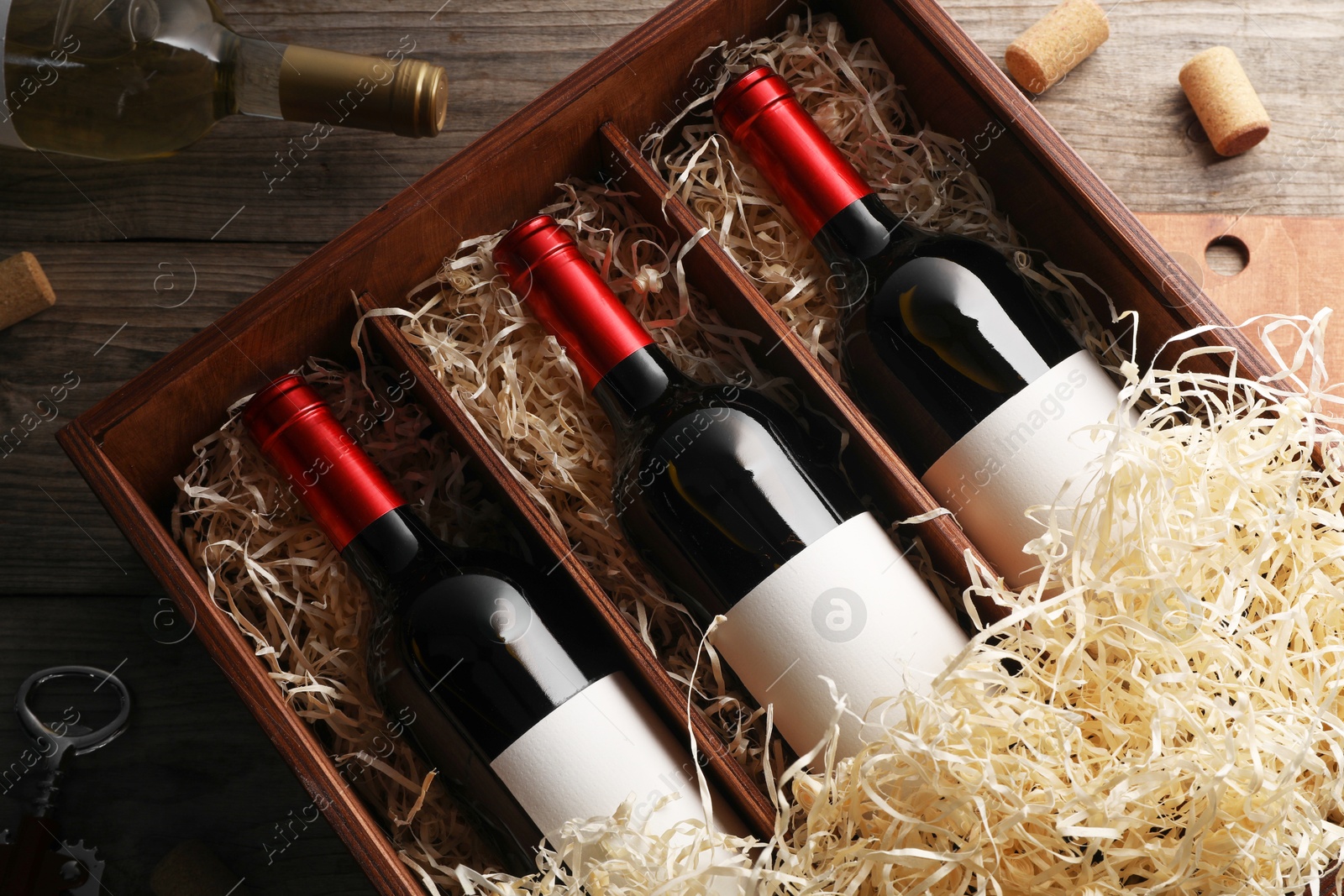 Photo of Box with wine bottles and corks on wooden table, flat lay