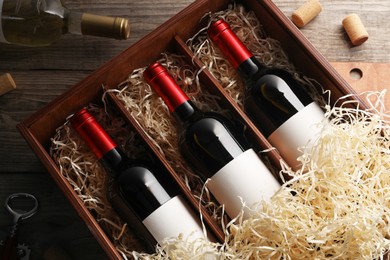 Photo of Box with wine bottles and corks on wooden table, flat lay