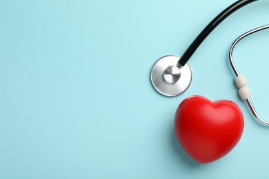 Stethoscope and red heart on light blue background, top view. Space for text