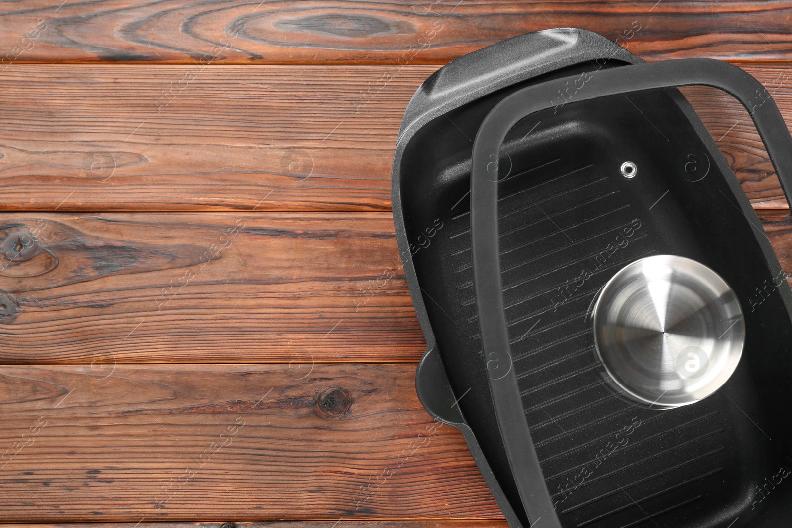 Photo of Black pot and glass lid on wooden table, top view. Space for text