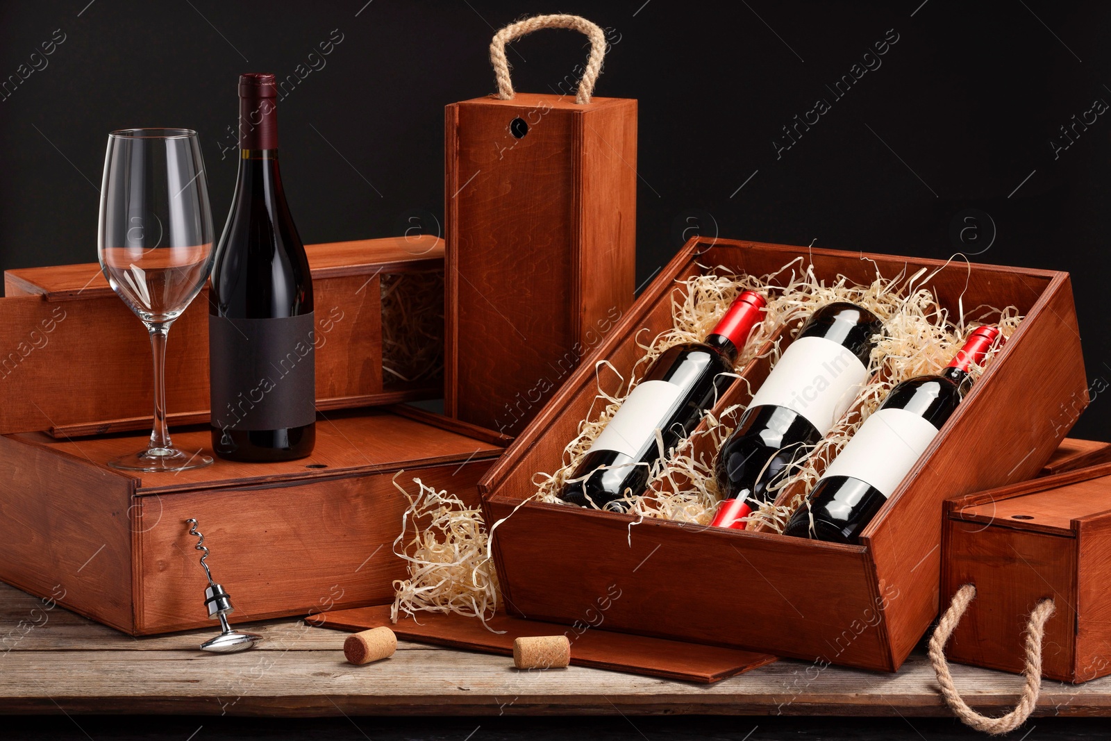 Photo of Boxes with wine bottles and glass on wooden table against black background