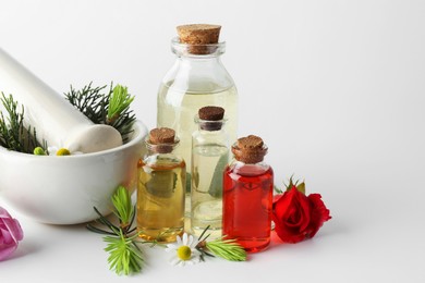 Aromatherapy. Different essential oils, flowers, mortar, pestle and fir twigs on white background