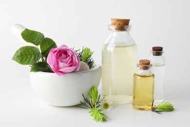 Photo of Aromatherapy. Different essential oils, flowers, mortar, pestle and fir twigs on white background