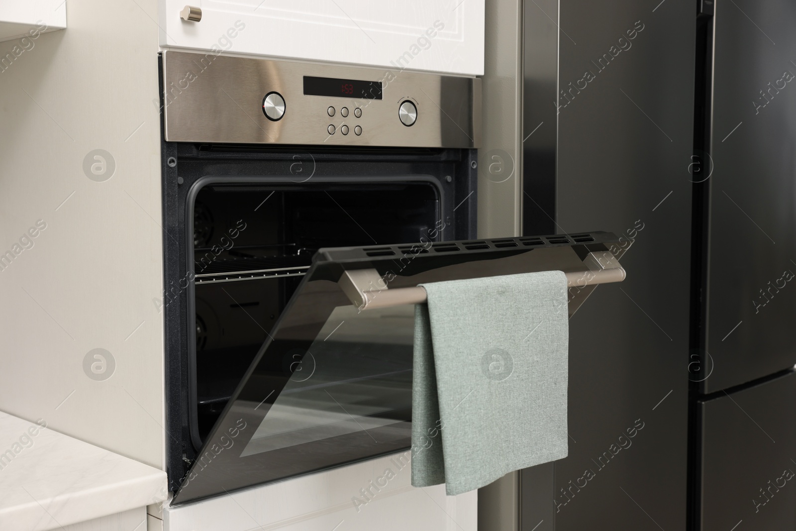 Photo of Open electric oven with towel in kitchen. Cooking appliance