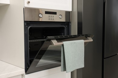 Open electric oven with towel in kitchen. Cooking appliance