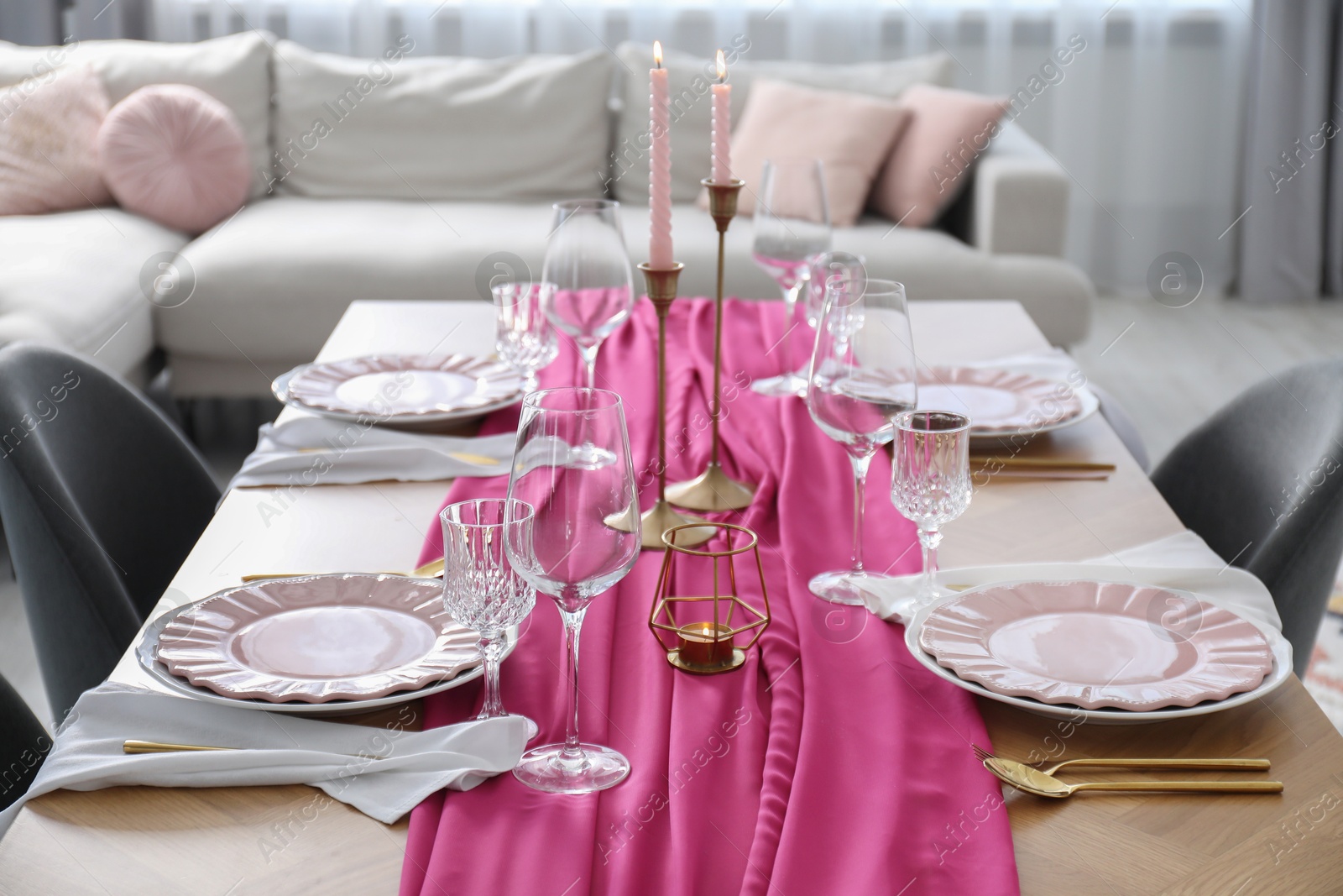 Photo of Beautiful table setting with burning candles and pink accent in dining room