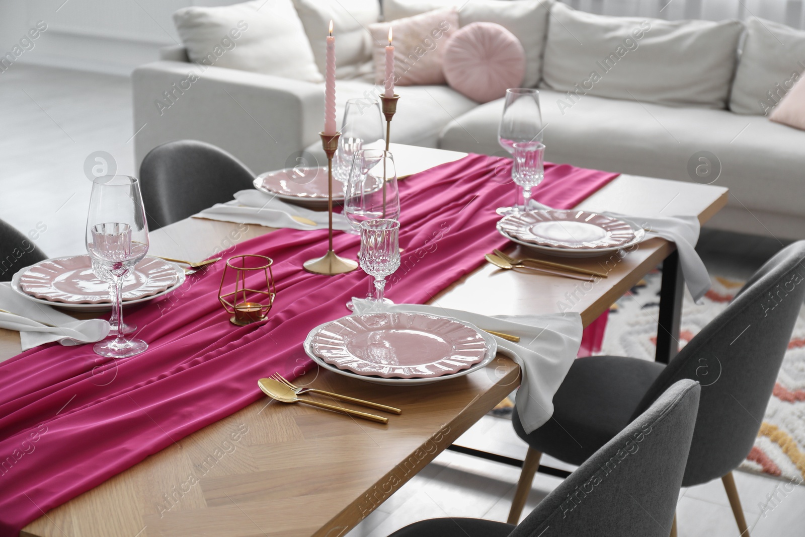 Photo of Beautiful table setting with burning candles and pink accent in dining room